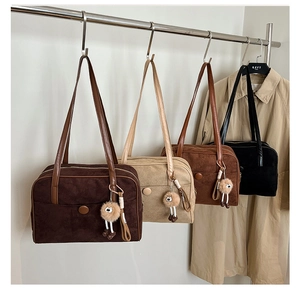 Close-up of four suede shoulder bags in brown and black with plush doll pendants