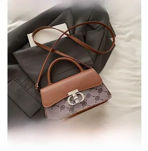 Detail of printed canvas small square bag with silver metal lock and leather strap
