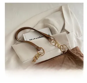 Close-up of brown quilted tote bag with gold chain strap and brand label on white blazer