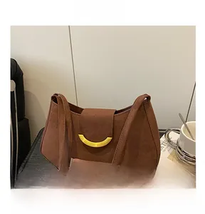 Detail view of brown suede underarm bag featuring a golden crescent metal buckle