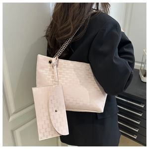 Detailed view of pink tote bag with letter print and golden chain strap on model