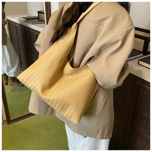 Detail view of woven wheat straw texture and spacious design on a tan tote shoulder bag