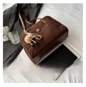 Detail showing the brown suede tote bag with plush charm and daily items on a bed