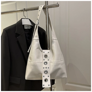 Detail of white leather hobo bag with silver grommets and studs on a wide shoulder strap