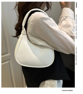 Close-up of white leather crescent hobo bag with silver logo text and smooth shoulder strap