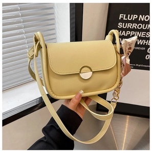 Detail of pale yellow crossbody bag with gold magnetic clasp and silk scarf accent