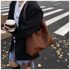Street style view of a brown woven shoulder tote bag for autumn urban commuting