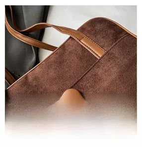 Detail of dark brown suede shoulder bag with leather trim and woven cord pendant