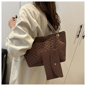 Detail of dark brown tote bag set with golden chain strap and letter pattern print