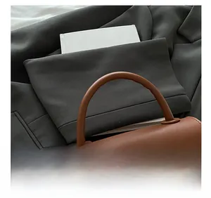 Detail of ergonomic rounded handle and silver rectangular metal lock on brown handbag
