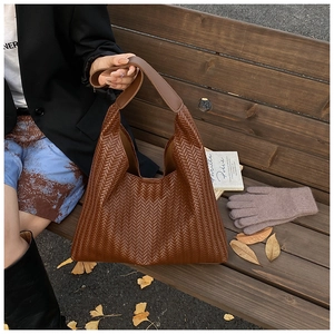 Brown herringbone woven tote bag styled with autumn leaves and knit gloves on a wooden bench