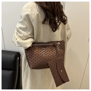 Detail of a brown leather tote with logo pattern and golden metal chain shoulder strap