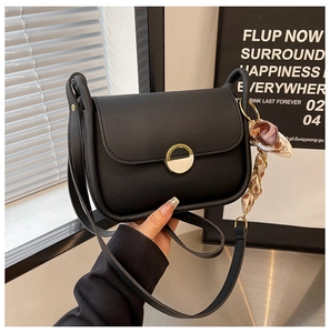 Detail of black leather saddle bag featuring gold hardware and silk scarf accent