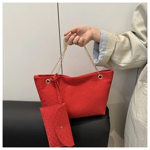 Close-up of red tote bag with embossed logo texture and elegant gold chain handles