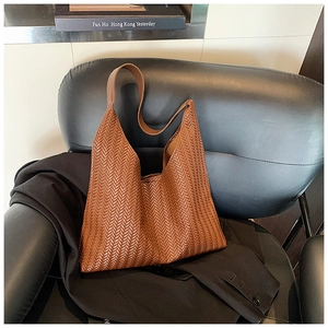 Detailed close-up of brown woven leather tote bag with V-shaped opening on a black chair