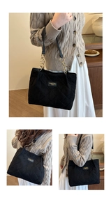 Detail view of black quilted velvet shoulder bag with gold chain and brand patch