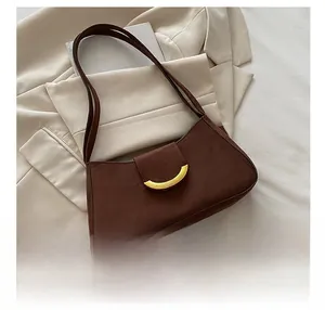 Detail of dark brown suede shoulder bag with gold metal clasp on aesthetic background
