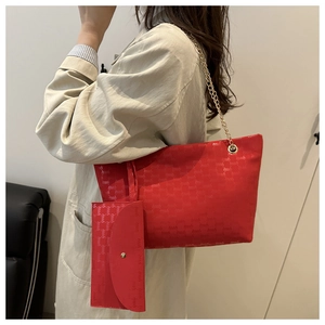 Detail of red tote bag and matching pouch set with textured logo print and gold chain