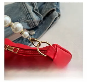 Detail of red bag with gold hardware, pearl handle, and sparkling rhinestone rings