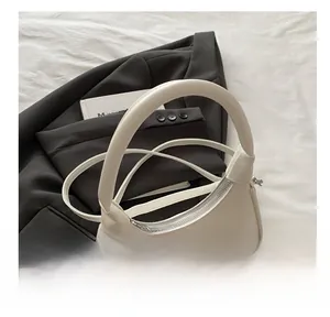 Detail view of white half-moon bag with lychee texture on black suit background