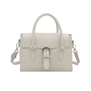 Minimalist beige crossbody handbag with top handle and silver buckle detail on white backdrop
