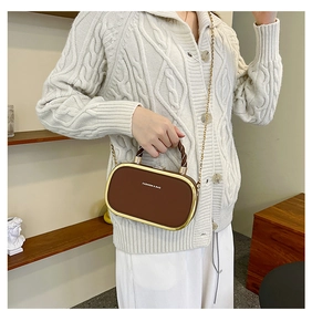 Detail of a brown leather oval handbag with gold metal frame and twisted handle
