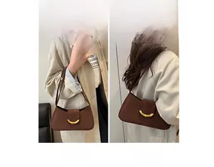Brown suede shoulder bag with crescent metal buckle and adjustable long strap detail