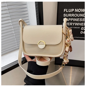 Detail of cream leather crossbody bag with gold lock and polka dot silk scarf handle
