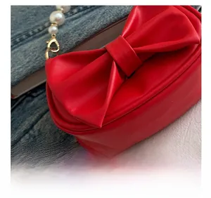 Close-up of a red PU leather bow handbag with pearl handle and fine stitching detail