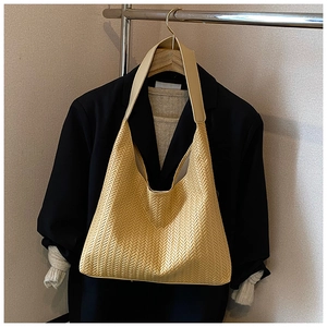 Detail of yellow woven hobo bag with herringbone texture hanging on metal hanger