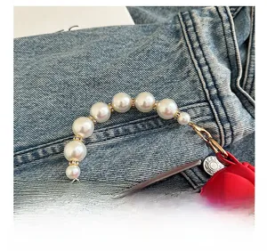 Detail of red pleated mini bag with gradient pearl handle and sparkling metal spacers