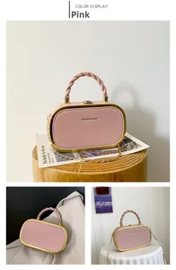 Close-up of pink fashion bag featuring golden chain strap and twisted handle detail