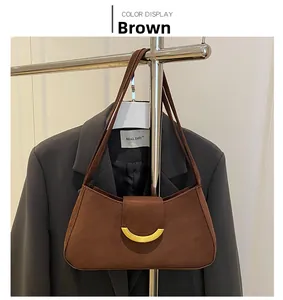 Detail view of brown suede baguette bag with gold crescent buckle on a display stand