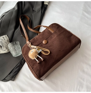Detail of dark brown tote bag with corduroy texture and decorative plush charm