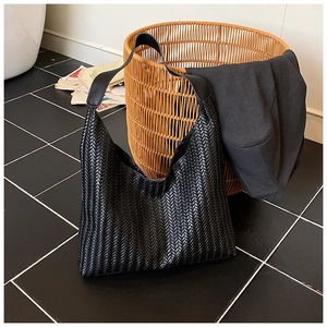 Détail du sac cabas en cuir tressé noir avec texture entrelacée et bandoulière large