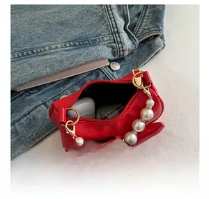 Detail view of red bow bag interior showing storage for lipstick and wireless earbuds