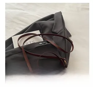Detailed view of deep brown leather bag with gold buckle on gray suit jacket