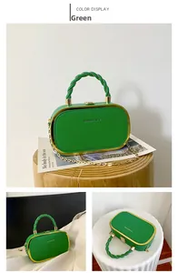 Detail view of green evening bag with gold metal frame, chain strap and snap closure