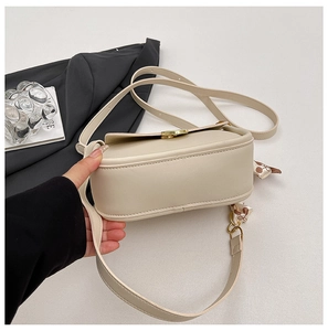 Detail of cream crossbody bag with gold twist lock and elegant brown printed silk scarf