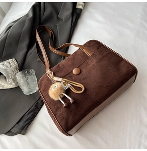 Detail of vintage brown frosted suede tote bag with leather trim and pompom charm
