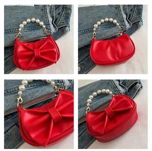 Detail view of red bow shoulder bag with white pearl handle and gold metal lock clasp