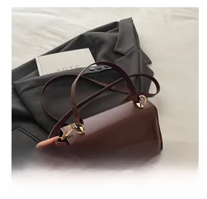 Detail of dark brown leather handbag with gold twist lock and sturdy comfortable handle