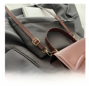 Close-up of golden metal buckle and matte brown leather texture on stylish crossbody bag