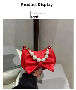 Detail of red bow-shaped leather bag featuring elegant pearl chain handle and top zipper