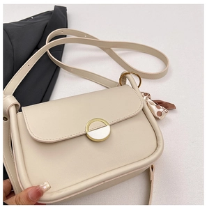 Detail of cream leather crossbody bag featuring gold metal buckle and brown floral scarf