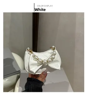 Detail of white mini handbag with bow design and elegant pearl beaded handle chain
