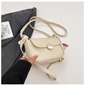Detail of cream leather crossbody bag with gold round buckle and decorative silk scarf