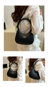 Detailed view of a minimalist black crescent bag with white fashion lettering and strap