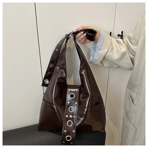 Detailed view of dark brown punk tote bag with large silver grommets and rivet hardware