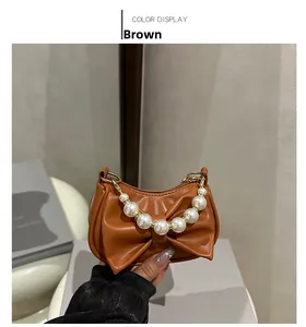 Brown handbag with oversized bow detail and elegant white pearl beaded top handle